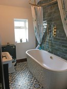 New bathroom refurbishment with green metro tiles and patterned floor tiles, by Thomson Properties