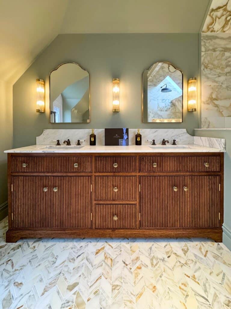 Wood double-basin vanity beneath two mirrors and wall lights.