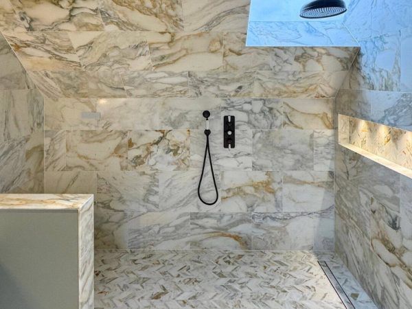 Modern steam room with marble walls and rainfall showerhead.