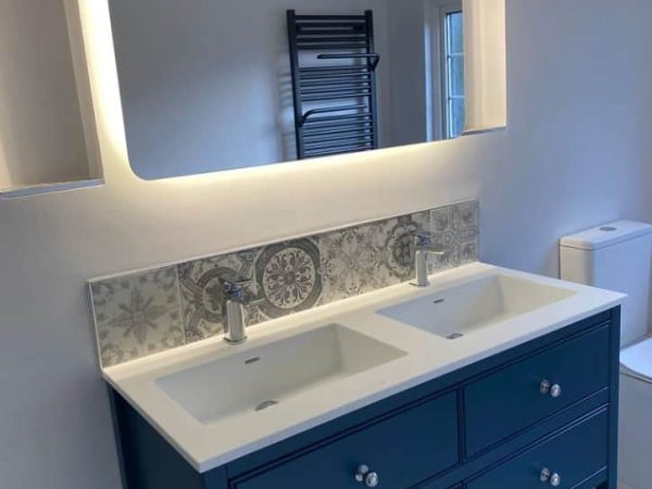 Blue bathroom vanity beneath a mirrored cabinet