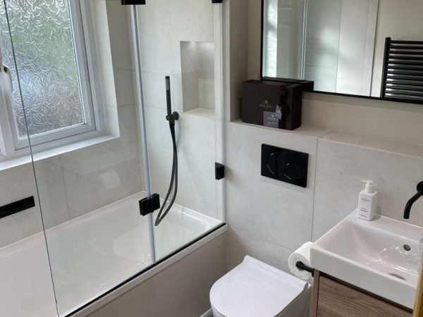 White bath beside a window with patterned floor tiles